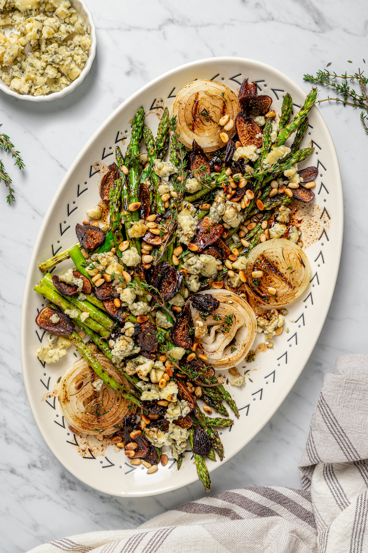 Grilled Asparagus with Onion recipe is topped with simple vinaigrette, blue cheese, black Mission figs, and toasted pine nuts. So flavorful! An asparagus salad with toppings and vinaigrette.