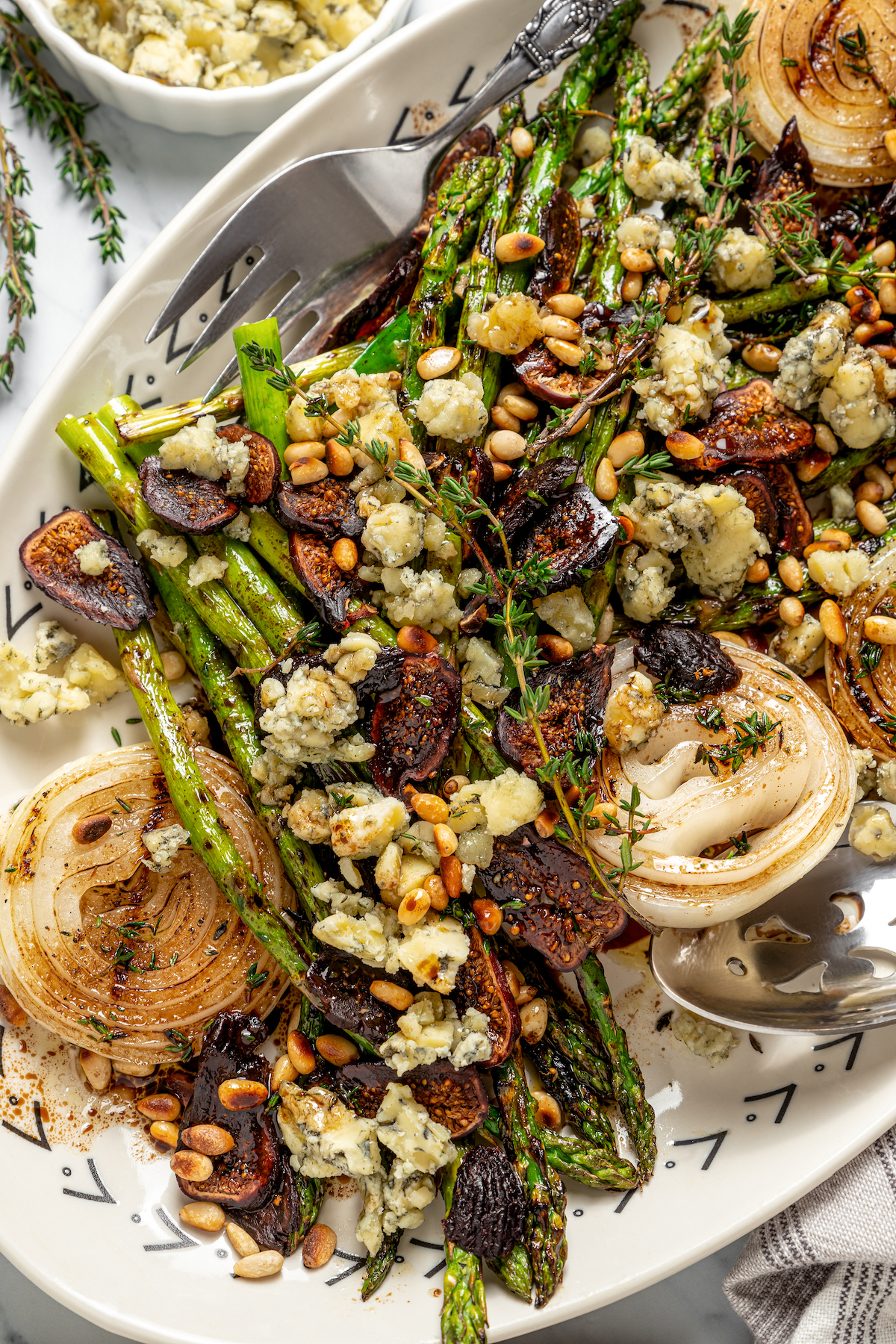 Grilled Asparagus with Onion recipe is topped with simple vinaigrette, blue cheese, black Mission figs, and toasted pine nuts. So flavorful! A summer salad with grilled vegetables, pine nuts, figs, and more.