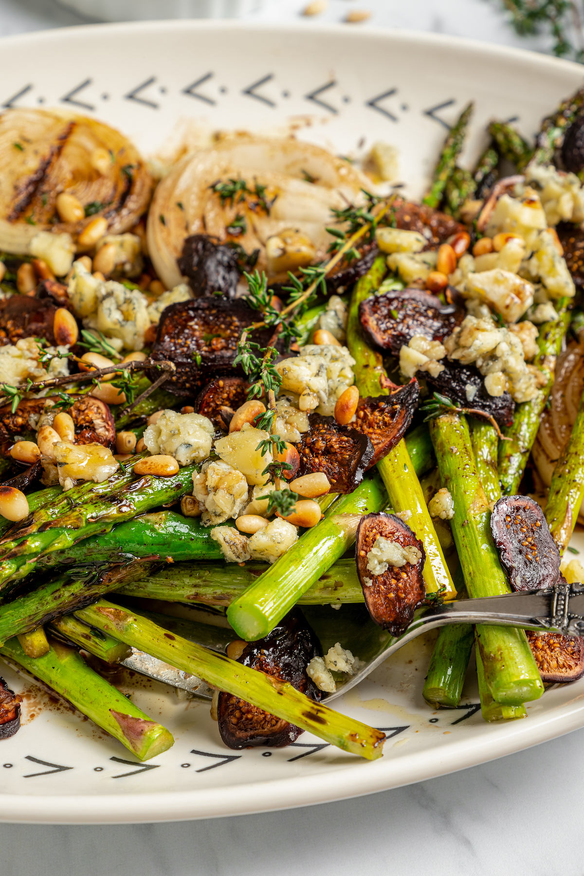 Grilled Asparagus with Onion recipe is topped with simple vinaigrette, blue cheese, black Mission figs, and toasted pine nuts. So flavorful! Grilled asparagus with onions, toppings, and vinaigrette.